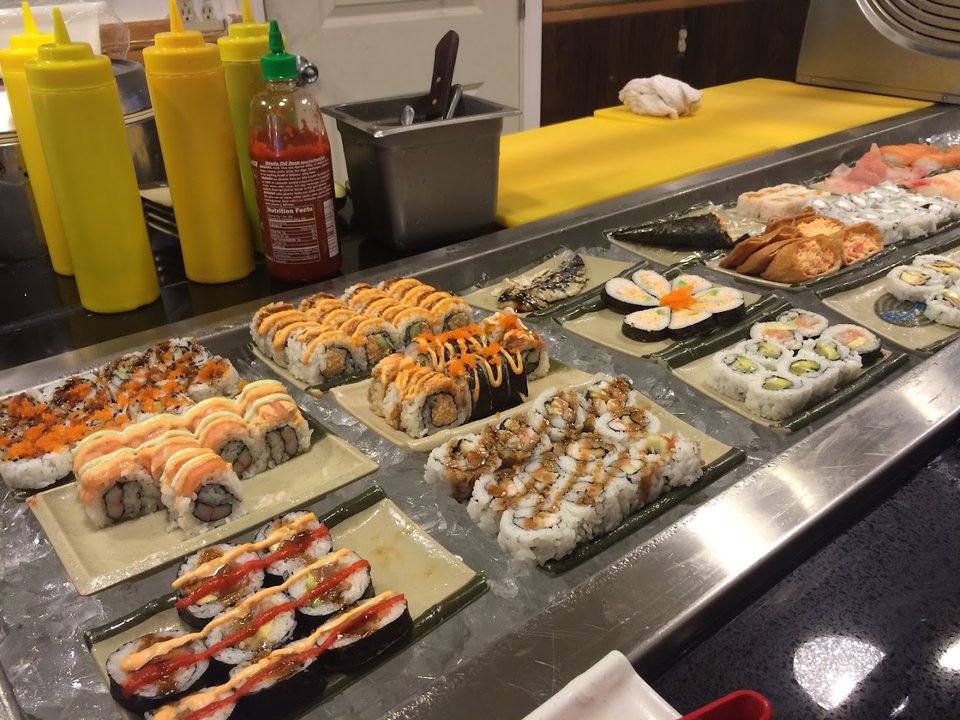 Sushi pieces arranged beside warm buffet trays.